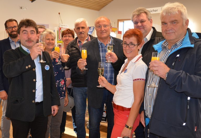 Bürgermeister Alfons Neumeier, die Leiterin der Bücherei Sabine Schlosser und weitere Vertreter der Gemeinde erheben das Glas auf eine erfolgreiche Zukunft der Gemeindebücherei.