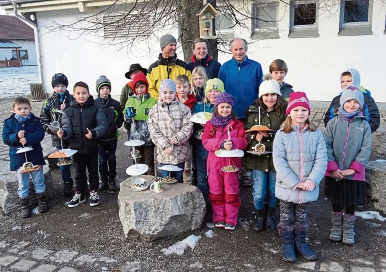 Kinder vom offenen Ganztag der Grundschule mit Vertretern des Gartenkauz Salching und den selbst gebauten Futterhäuschen