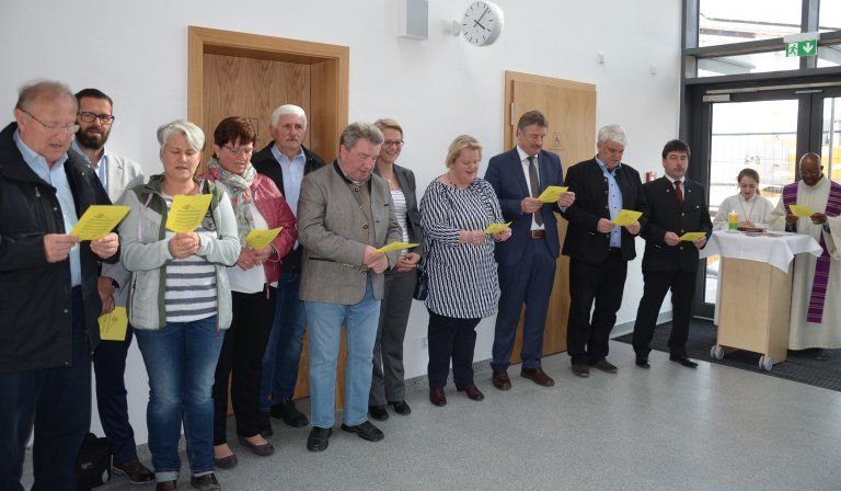 Pfarrer Dr.Raphael Mabaka beim Segensgebet im Beisein von Bürgermeister Alfons Neumeier, Stellvertreter Gerolf Weinzierl, Schulrat Konrad Rieder, Rektorin Bettina Deinhart, Leiterin Betreuung Katrin Primbs und Gemeinderäten