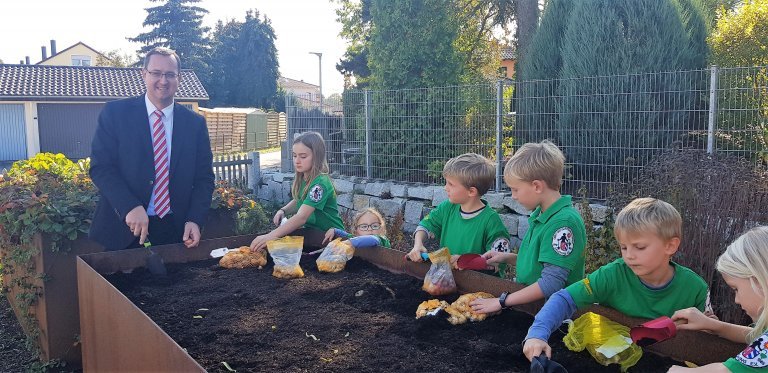 Geschäftsstellenleiter Klaus Simmel und Kinder beim Pflanzen von Blumenzwiebeln