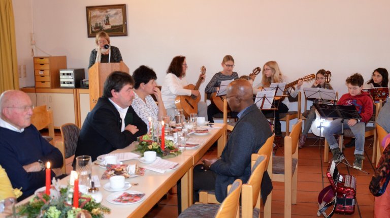 Teilnehmer des Seniorennachmittags und im Hintergrund Kinder mit Instrumenten