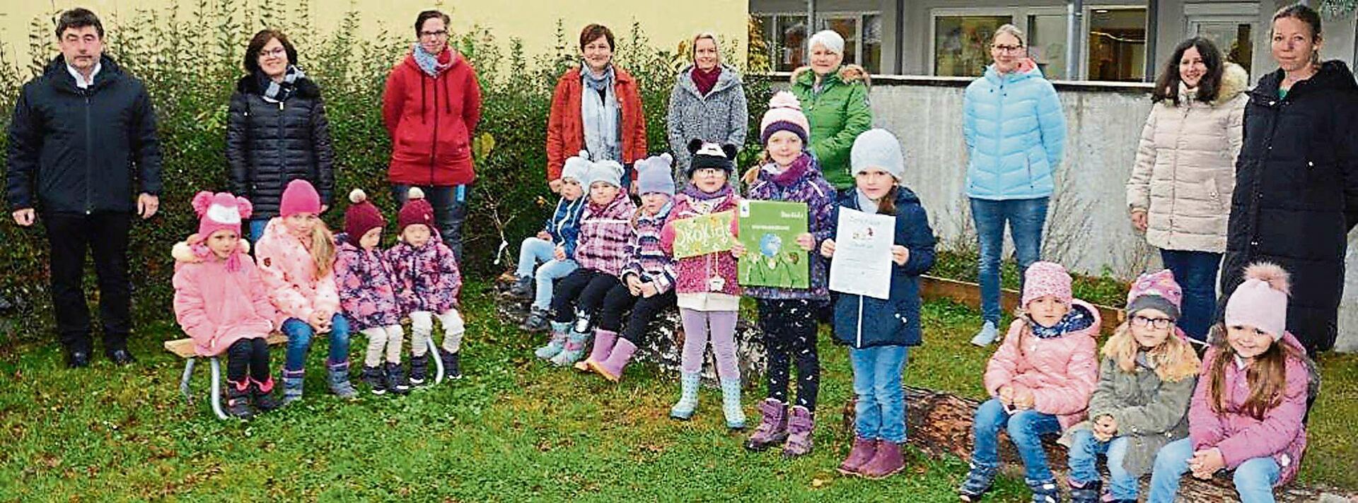 Salchings Bürgermeister Alfons Neumeier (links), 2. Bürgermeisterin Petra Grießbaum (Vierte von rechts), Kita-Leiterin Gabriele Ertl (Vierte von links), die Elternbeiräte Bettina Meilinger und Kristine Krannich (Dritte und Fünfte von rechts) sowie Erzieherinnen und einige der stolzen „ÖkoKids“. Foto: Josef Bierl/Straubinger Tagblatt